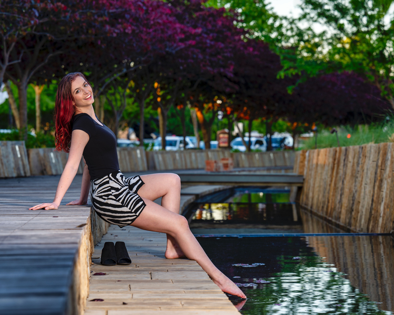 Красивая девушка опустила ноги в воду