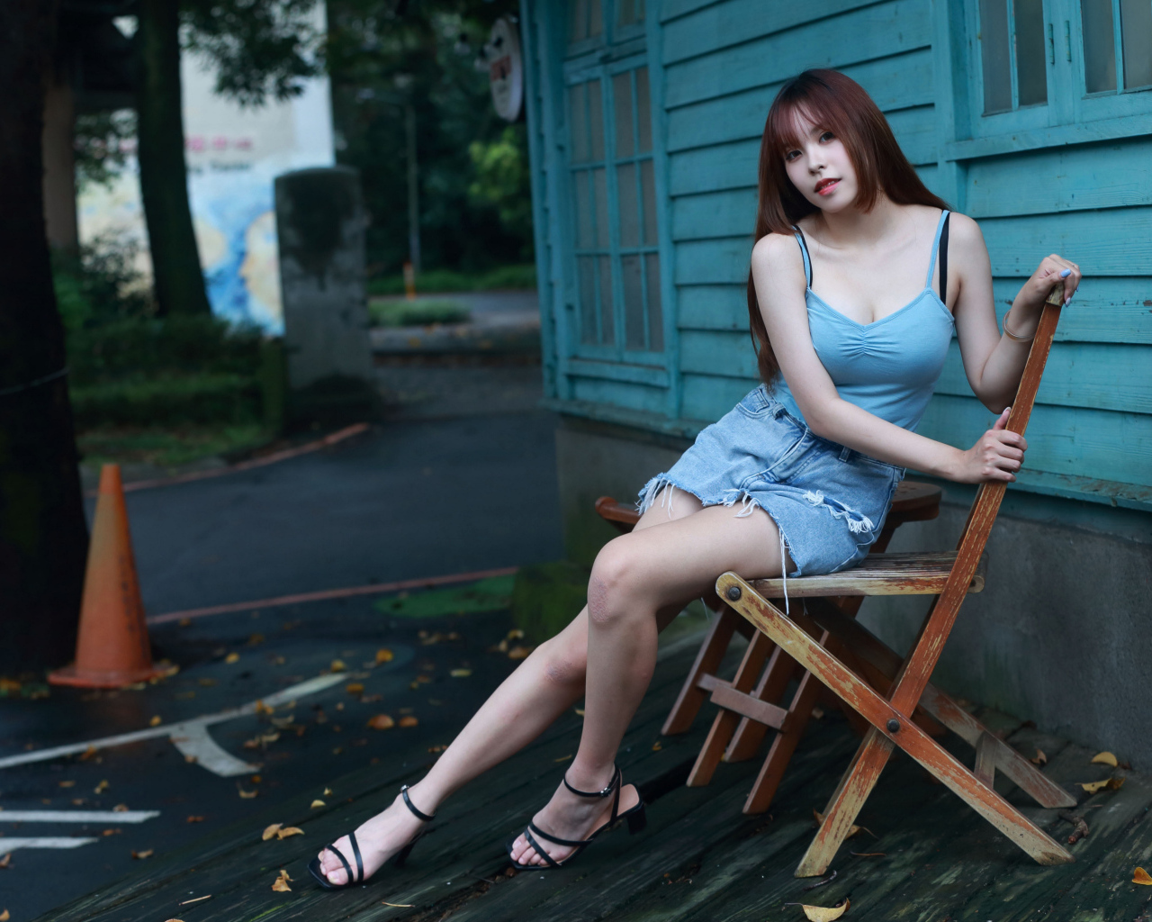 Красивая девушка сидит на стуле у дома