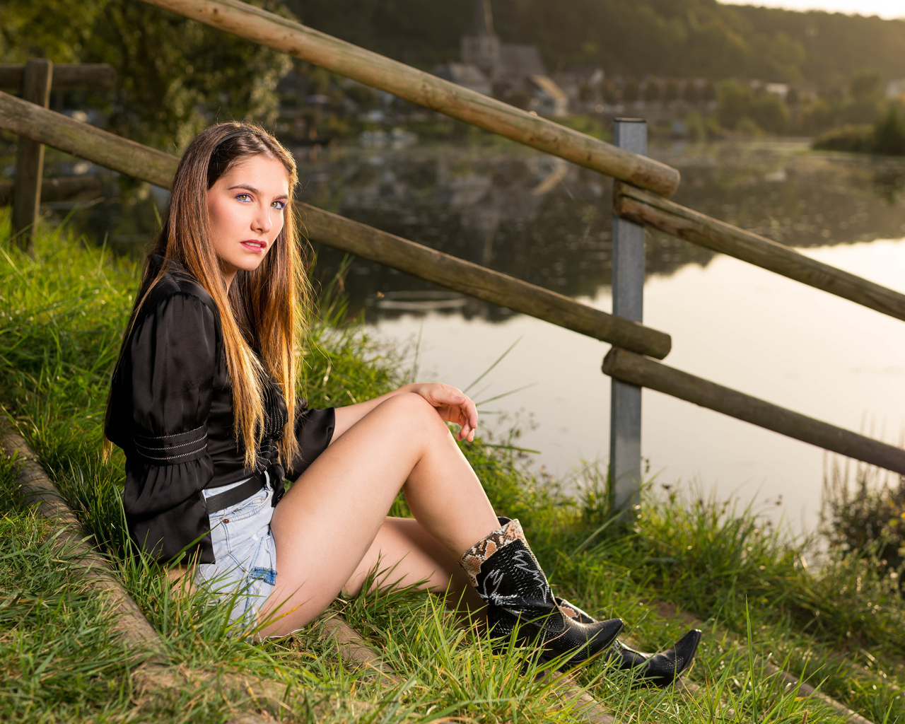 Красивая девушка сидит на берегу реки