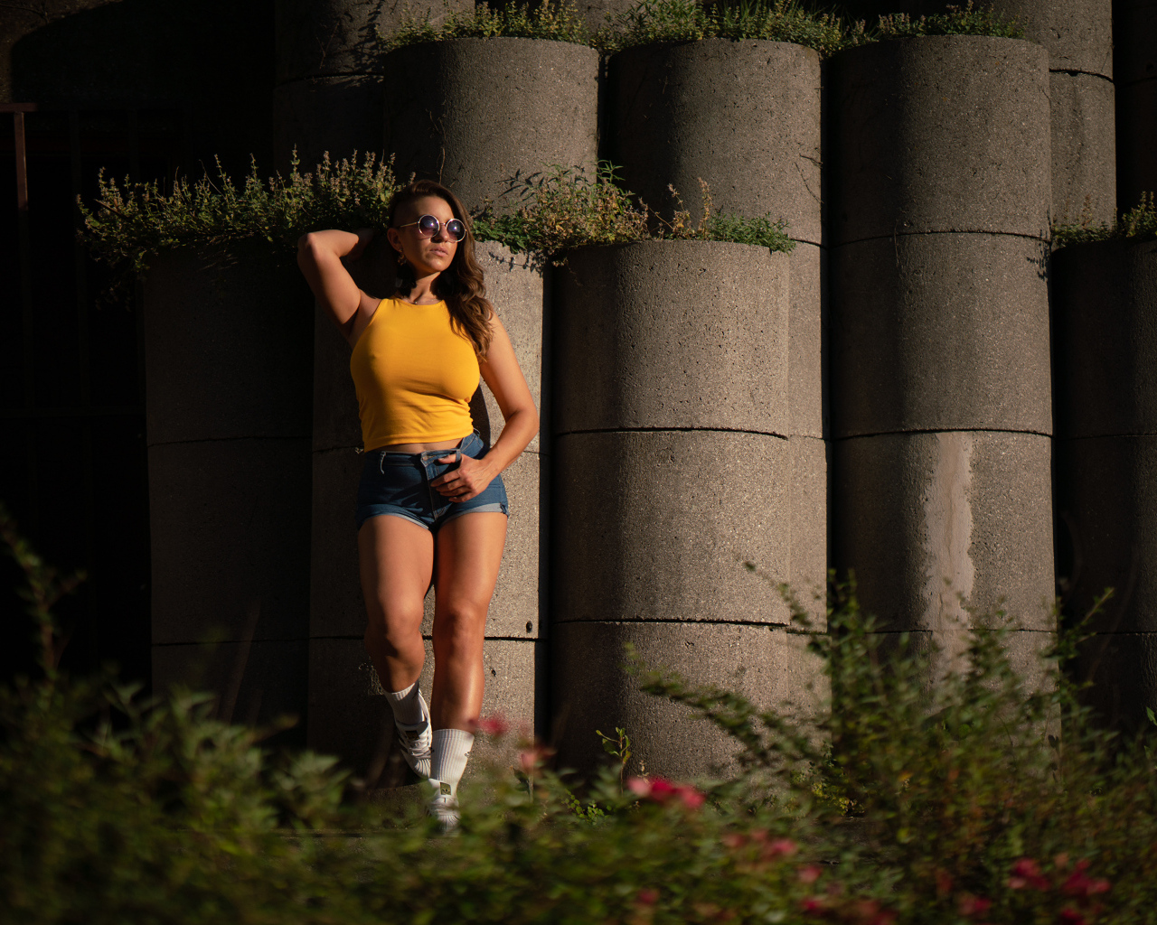 Красивая девушка в очках стоит у стены