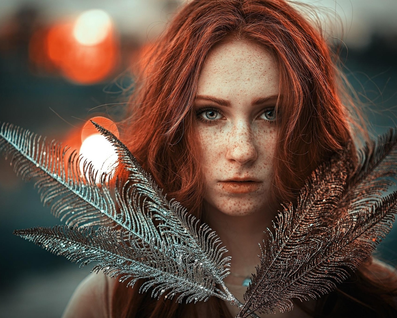 Яркая рыжеволосая девушка с перьями в руках