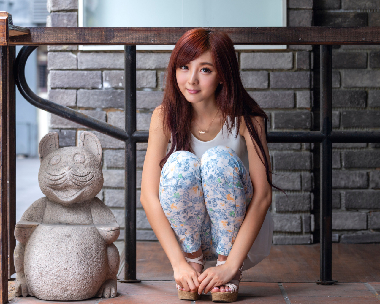 Милая девушка азиатка позирует со статуэткой