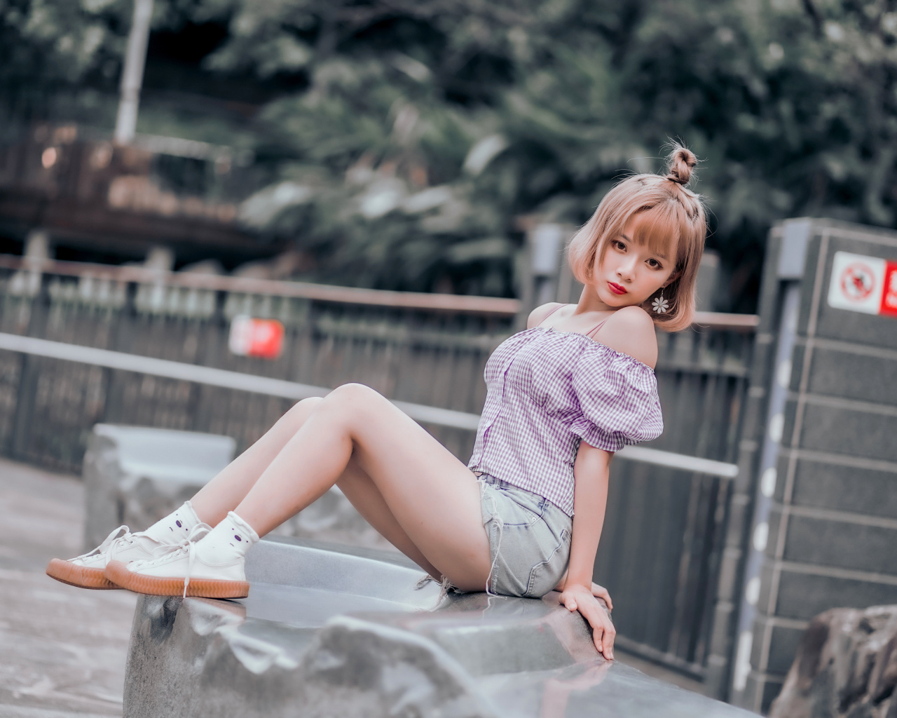 Милая девушка азиатка сидит на камне