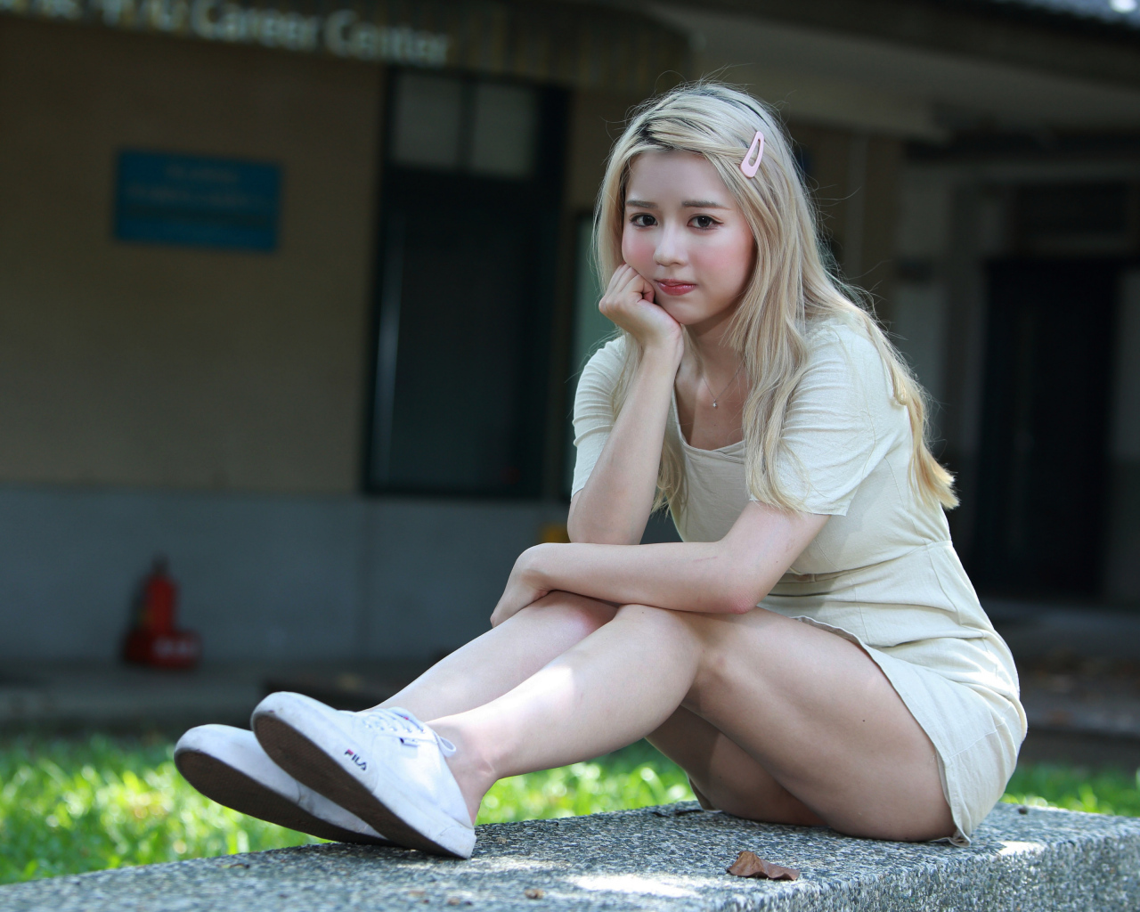 Милая азиатка сидит на холодном бетоне