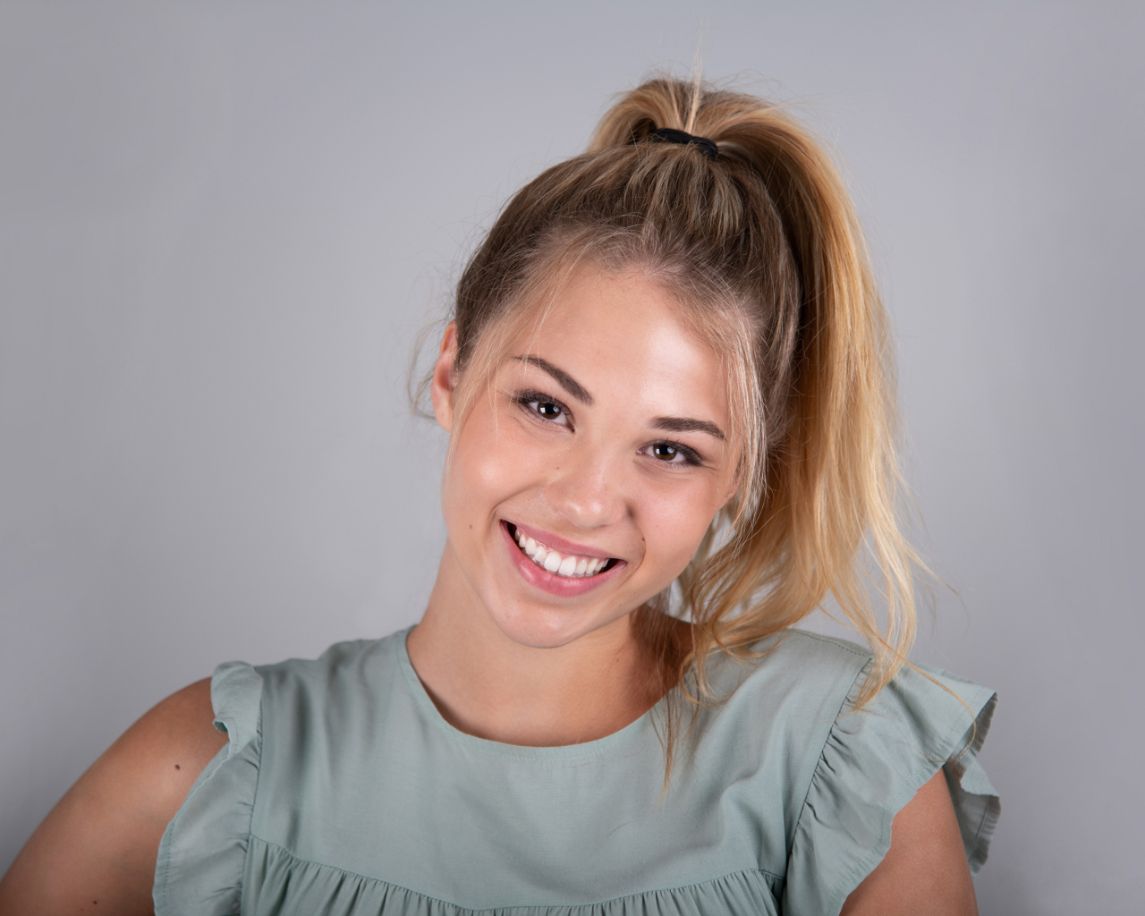 Милая блондинка на сером фоне