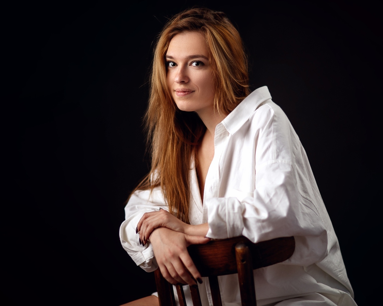 Милая девушка в белой рубашке сидит на стуле