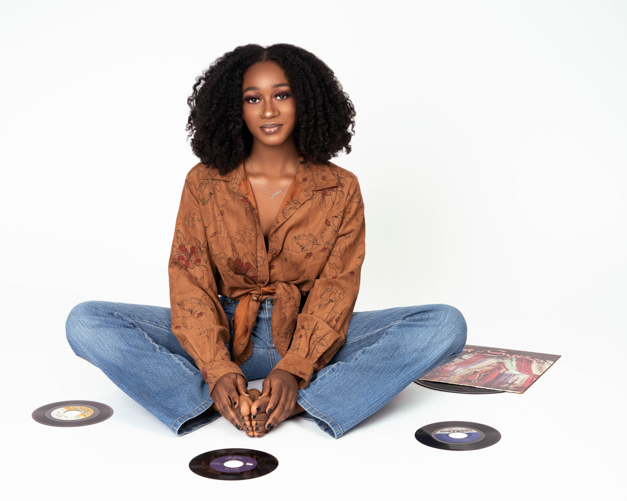 Темнокожая девушка сидит на белом фоне с пластинками