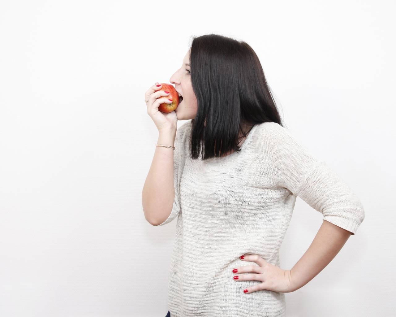 Девушка кусает красное яблоко 