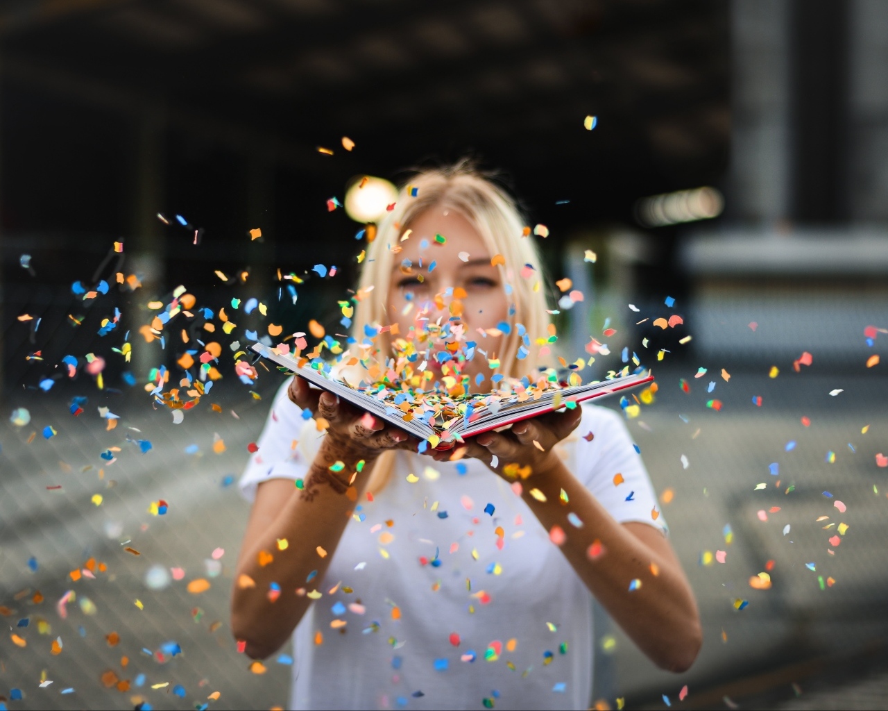Девушка сдувает конфетти с книги 