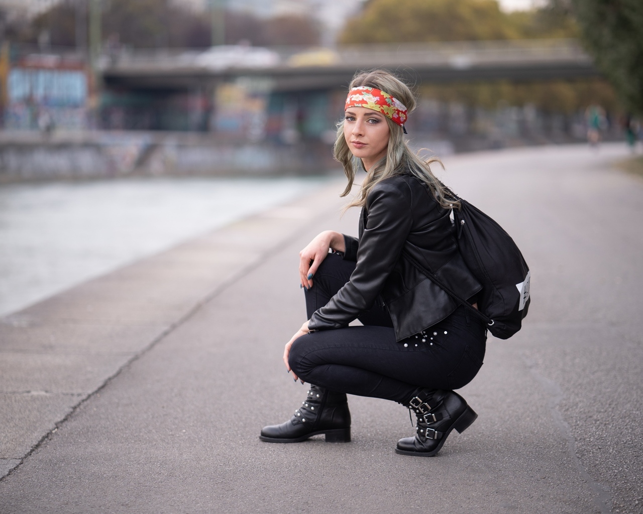 Девушка в черном костюме сидит на корточках