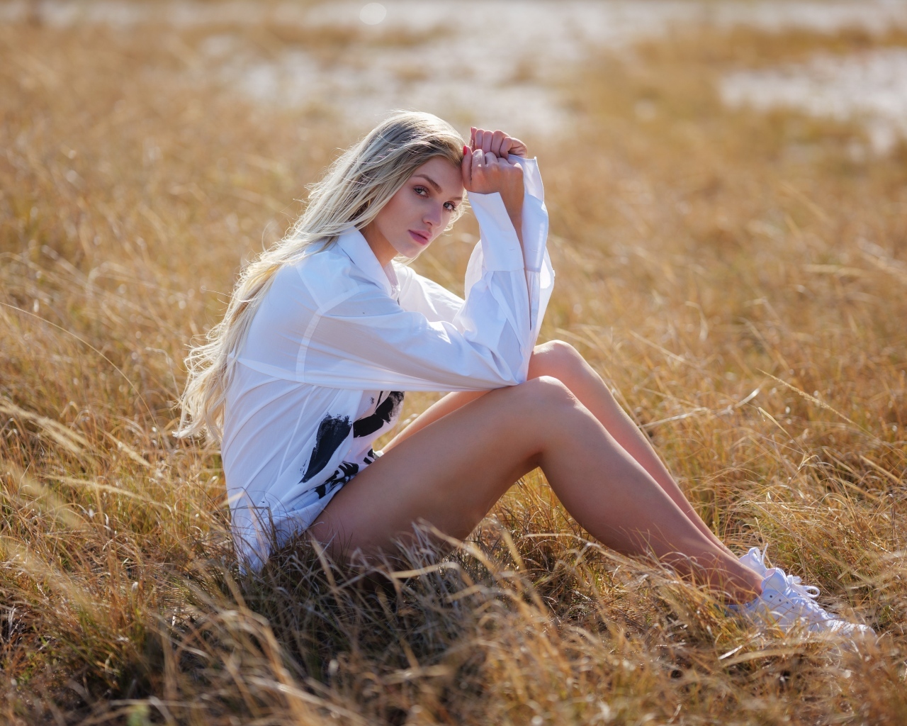 Девушка в белой блузке сидит на траве