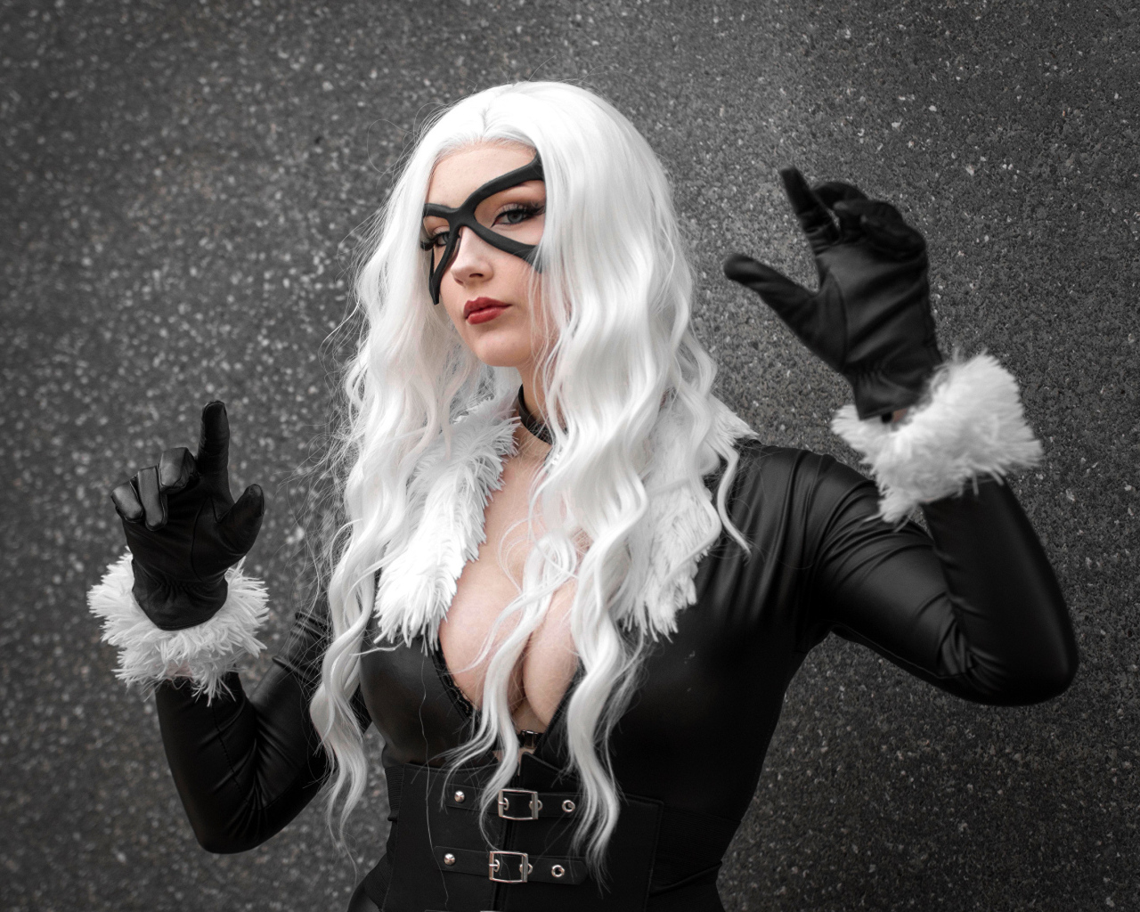 Девушка в белом парике в черном костюме у серой стены