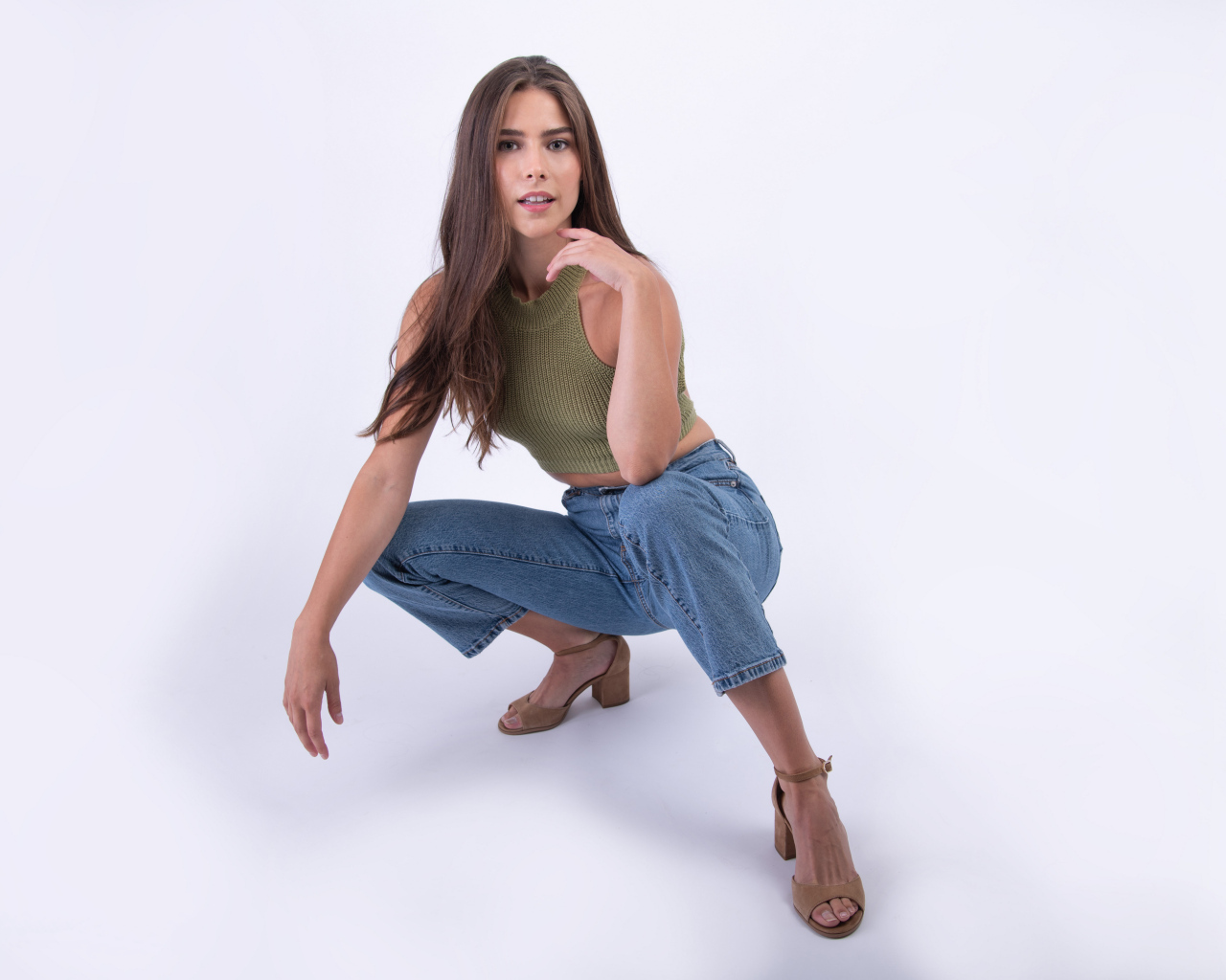 Девушка сидит на корточках на белом фоне