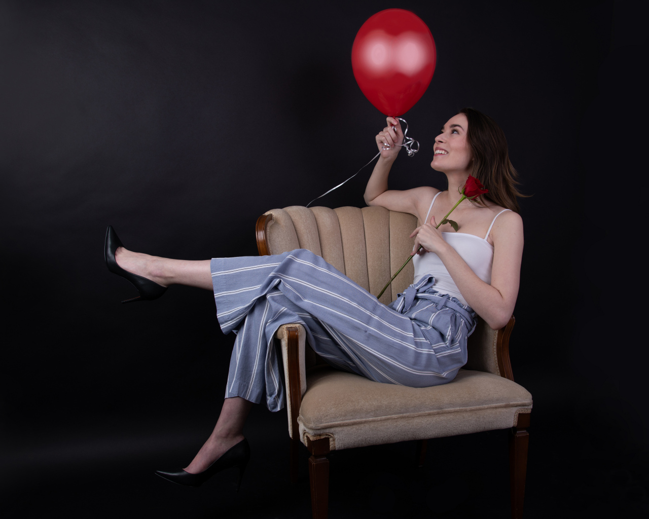Девушка с шариком и розой сидит в кресле