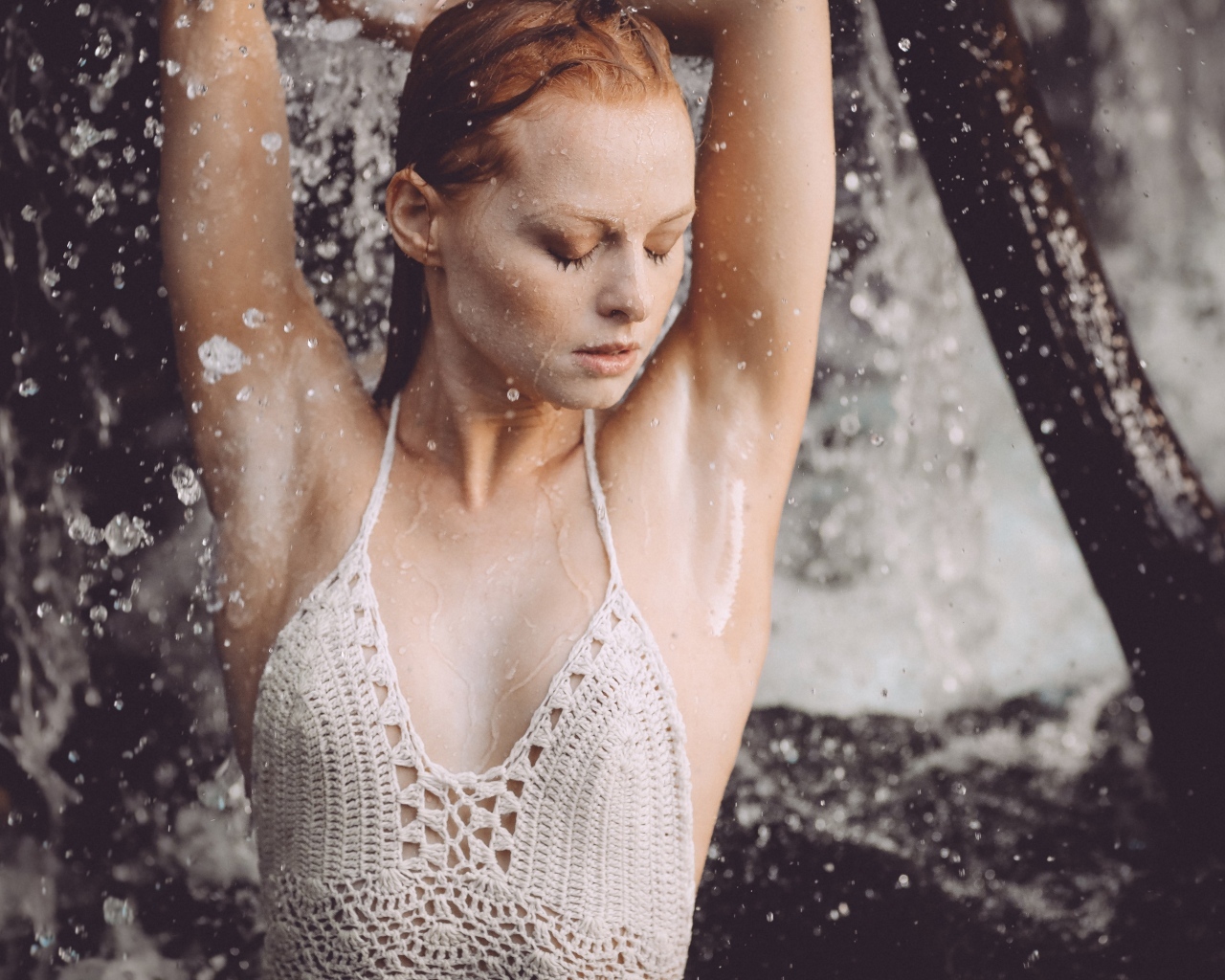 Рыжеволосая девушка в брызгах воды