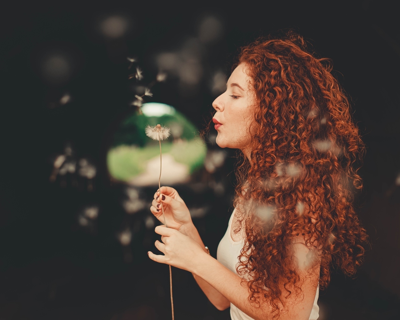 Рыжеволосая девушка с одуванчиком в руке