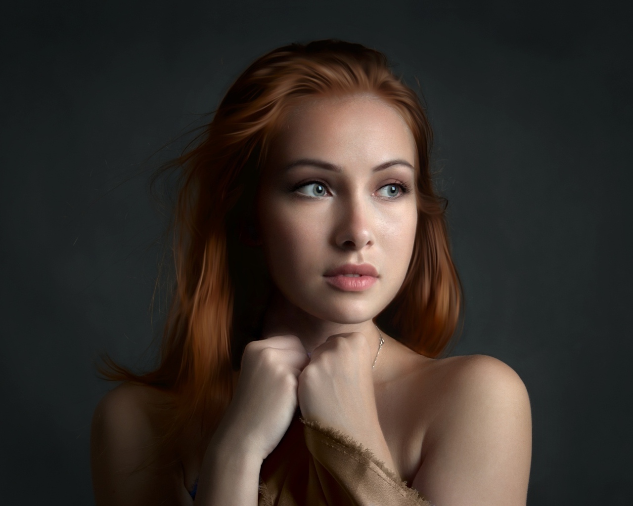 Рыжеволосая девушка с красивыми серыми глазами на сером фоне