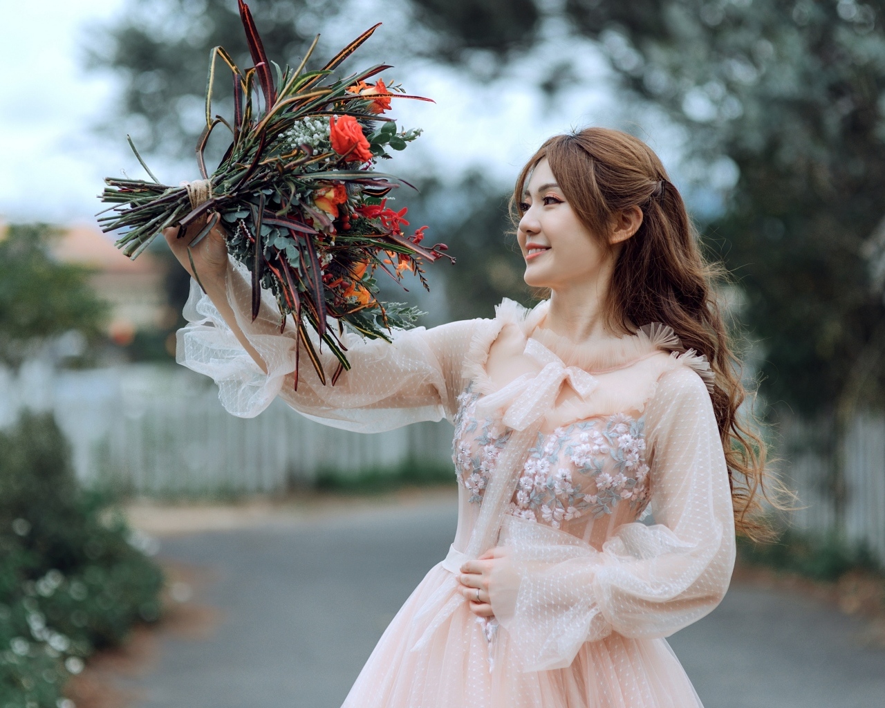 Улыбающаяся девушка азиатка в розовом платье с букетом