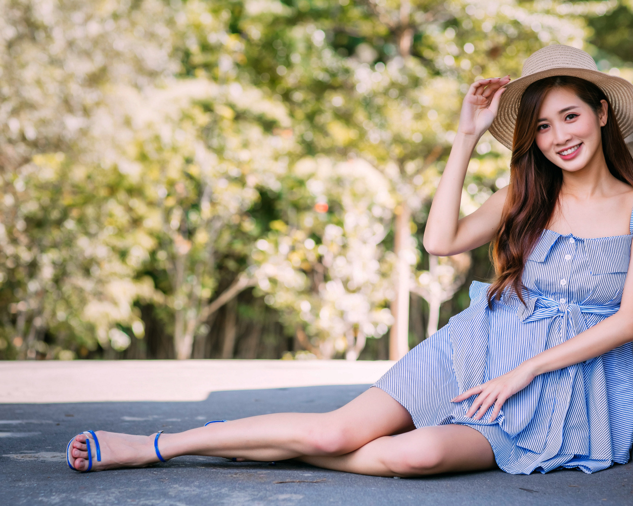 Улыбающаяся девушка азиатка сидит на асфальте