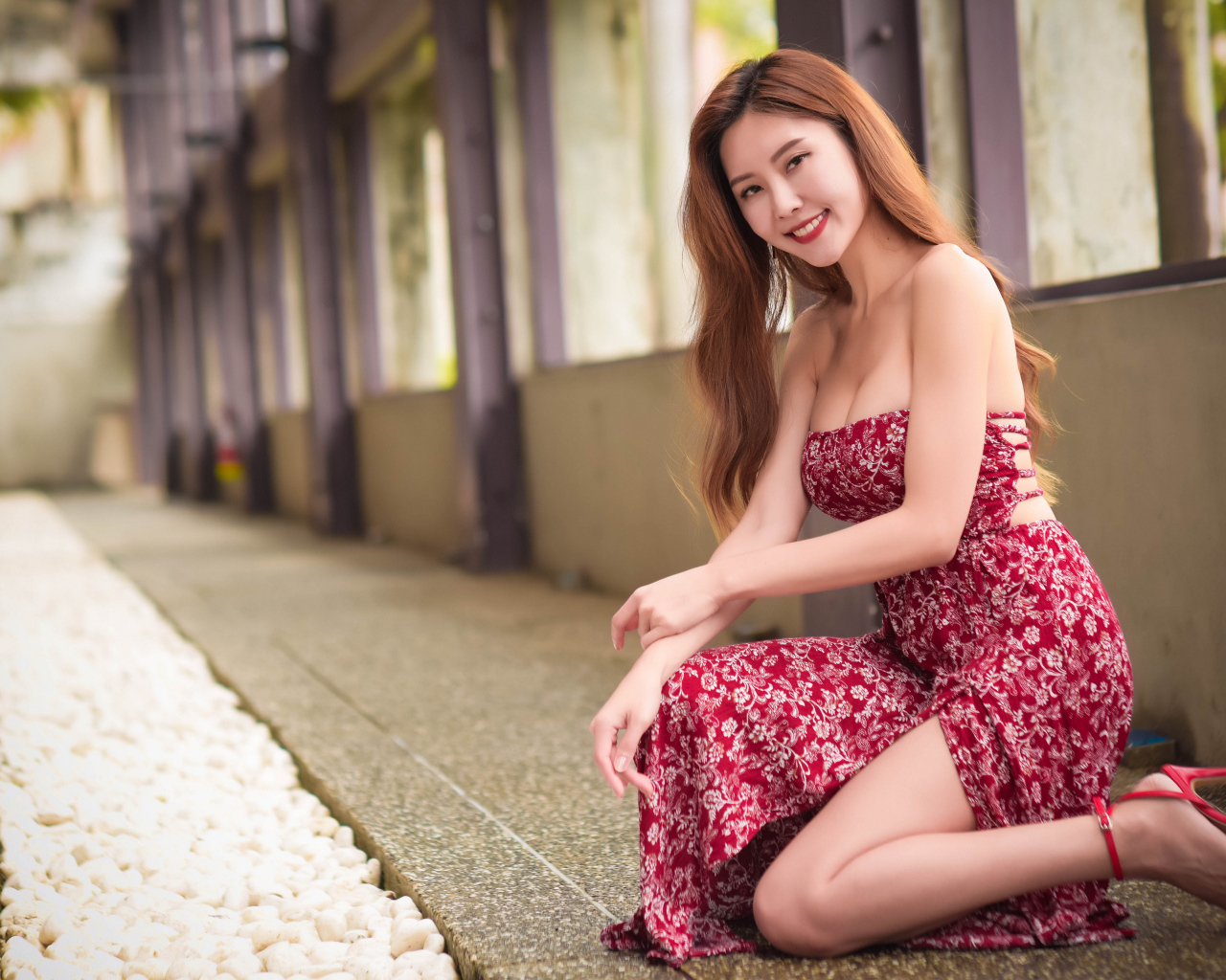 Улыбающаяся азиатка в красном платье у окна 