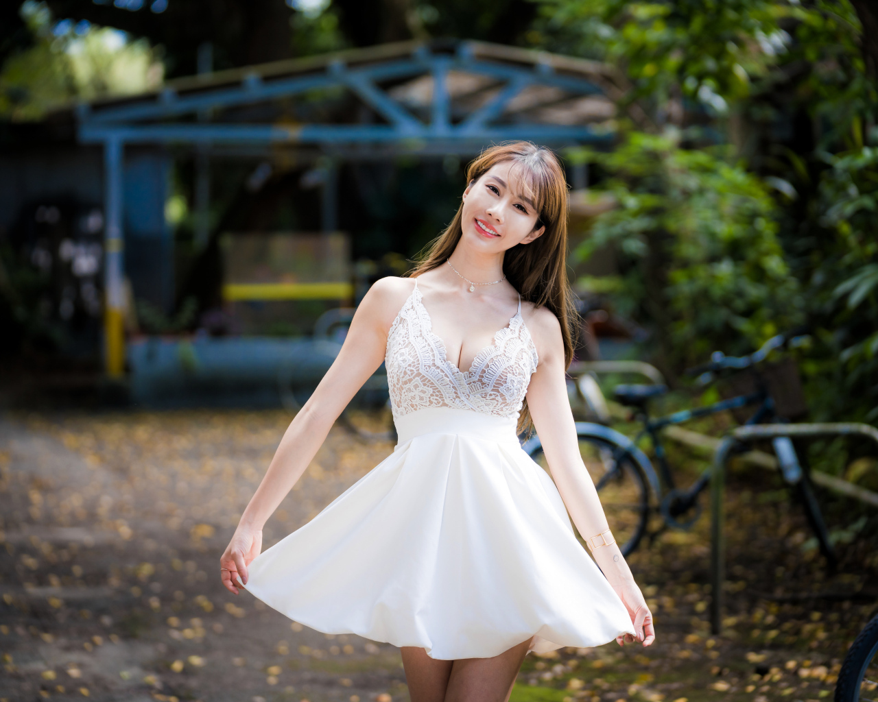 Улыбающаяся азиатка в белом платье в парке