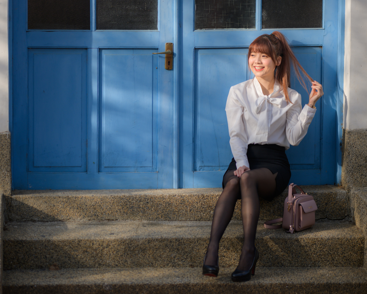 Улыбающаяся азиатка сидит на ступеньках