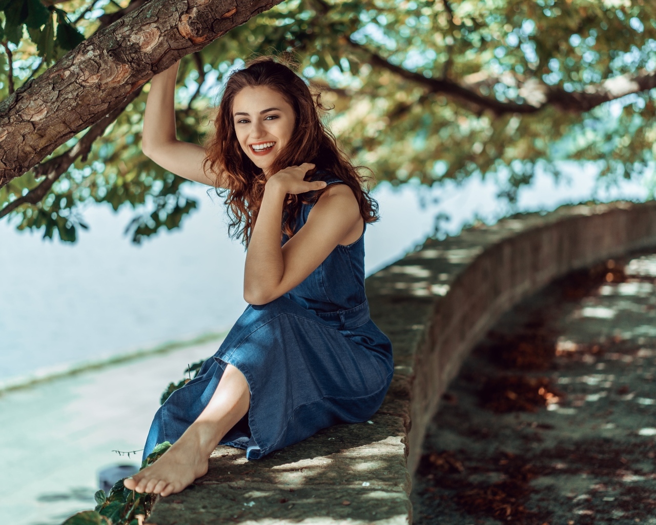 Улыбающаяся девушки сидит у дерева