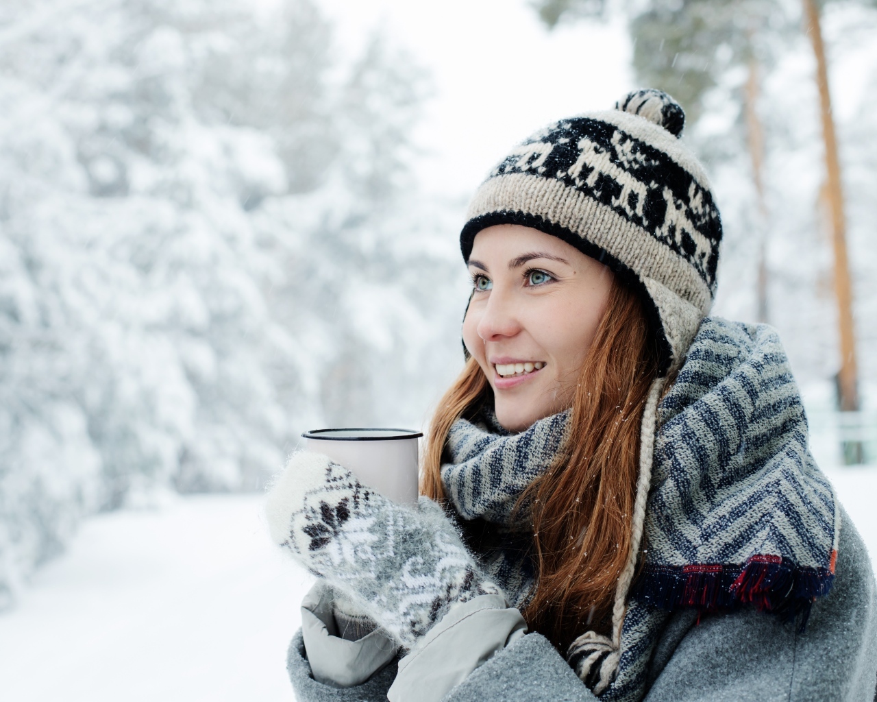 Улыбающаяся девушка с чашкой кофе зимой