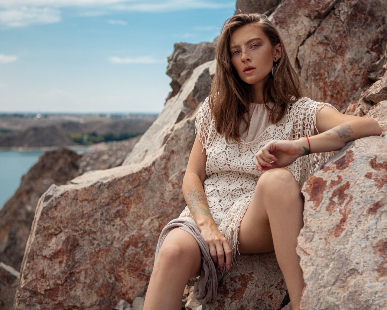 Молодая девушка сидит на камнях