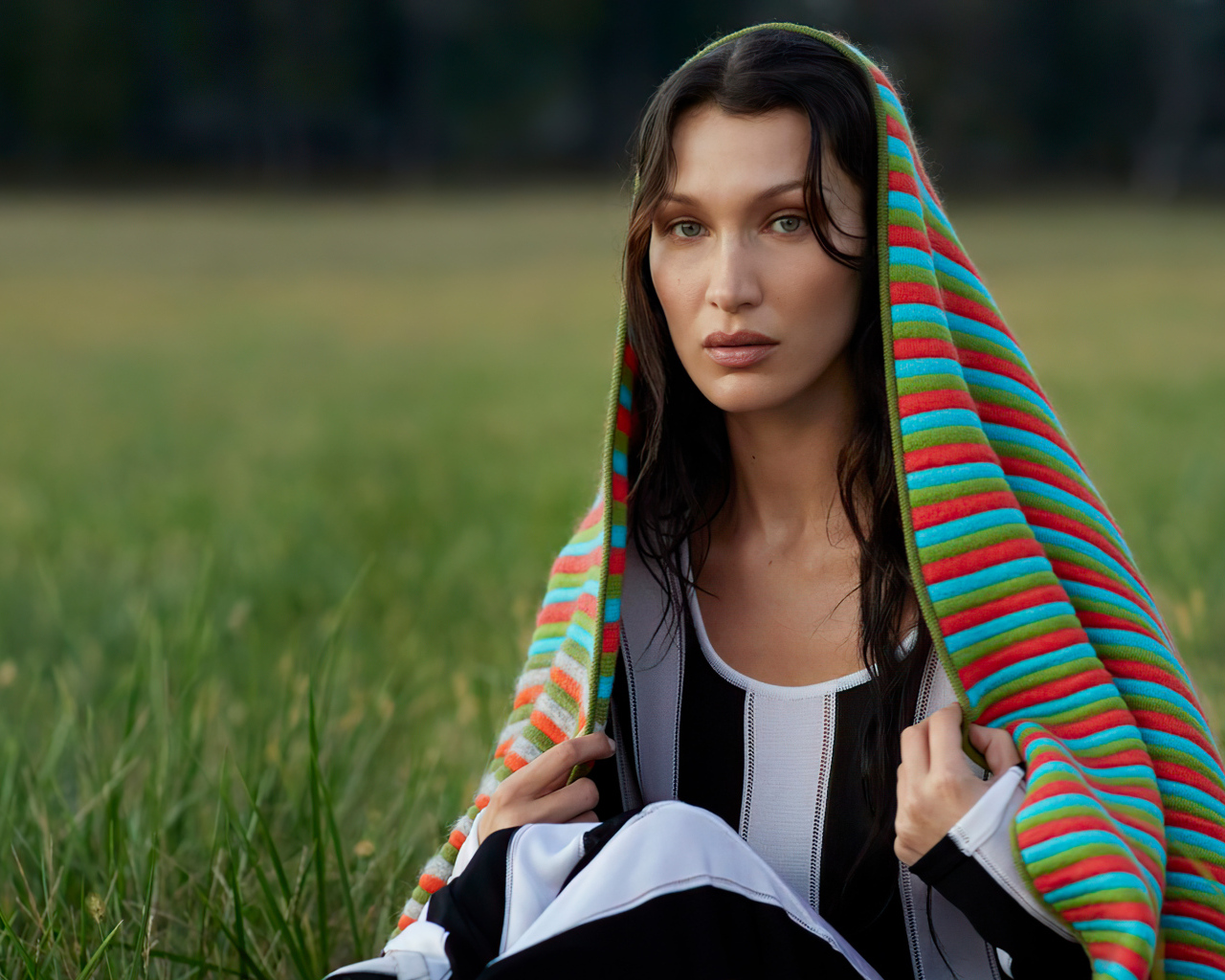 Модель Белла Хадид сидит на траве под пледом