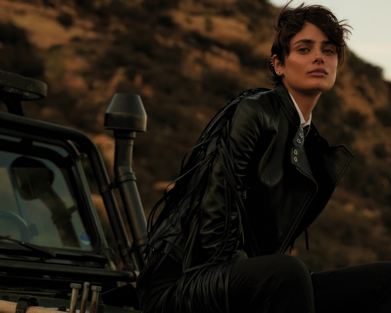 Модель Тейлор Хилл в черной куртке сидит на машине