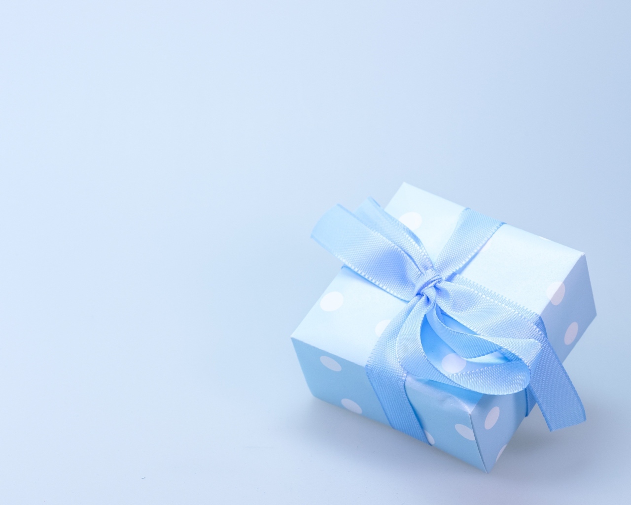 Коробка для подарка с голубой лентой на сером фоне