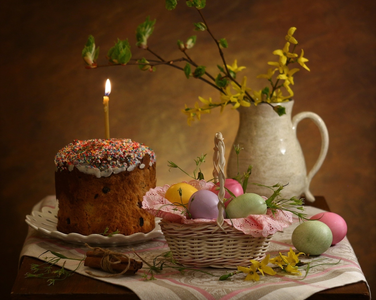 Кулич со свечой и крашеными яйцами на столе на Пасху