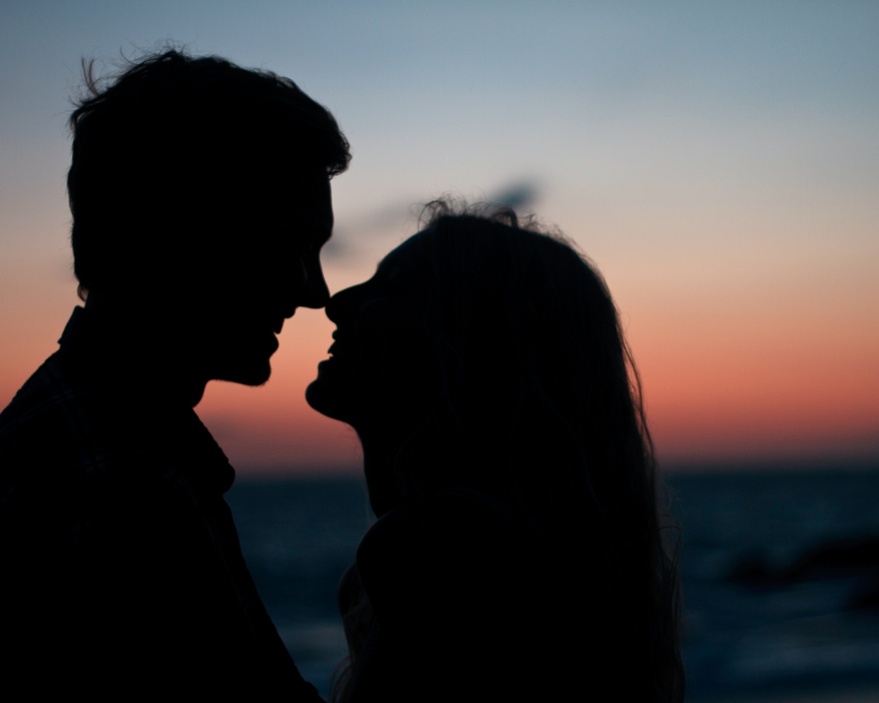 Влюбленная пара стоит на фоне заката в сумерках