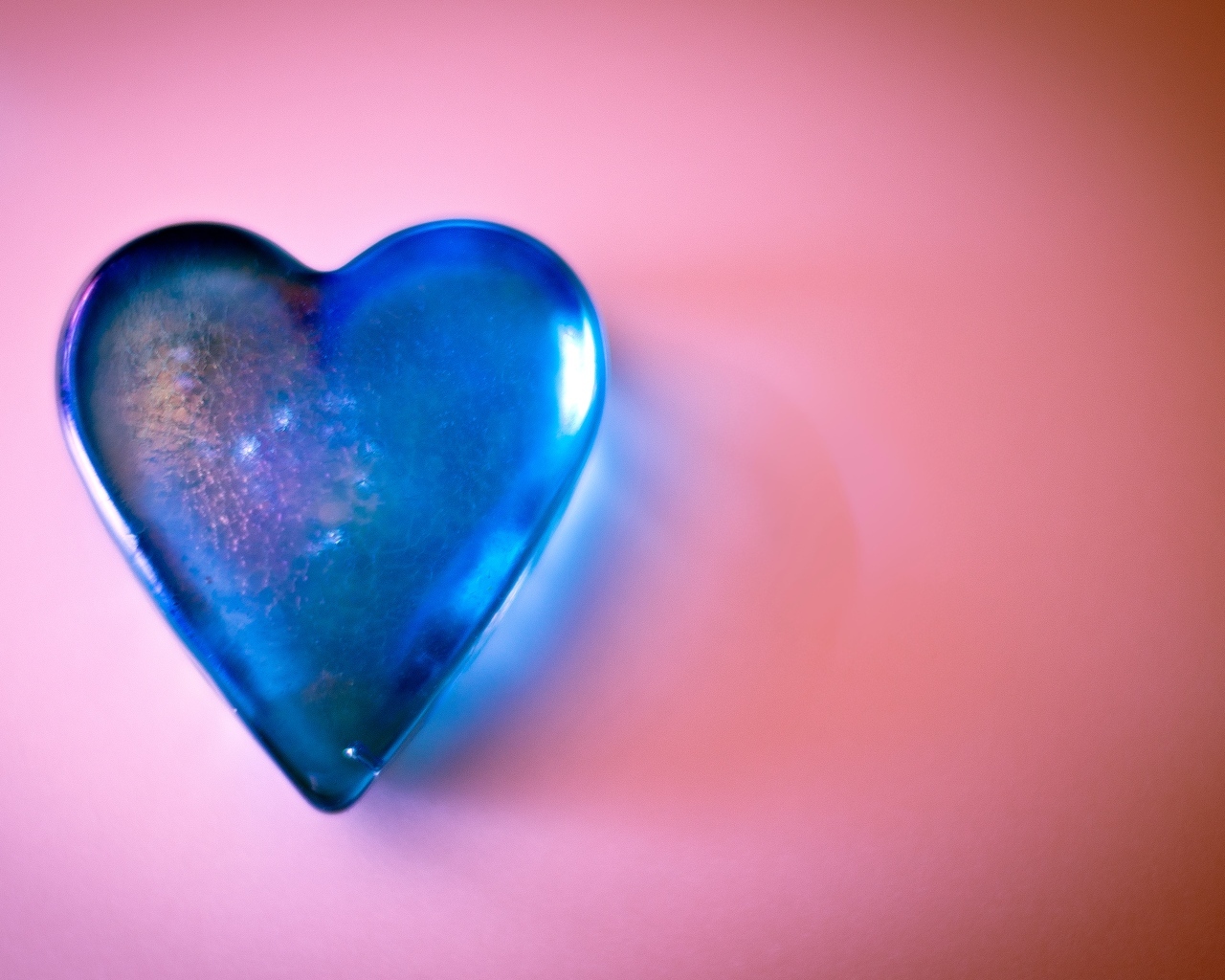 Синее стеклянное сердце на розовом столе
