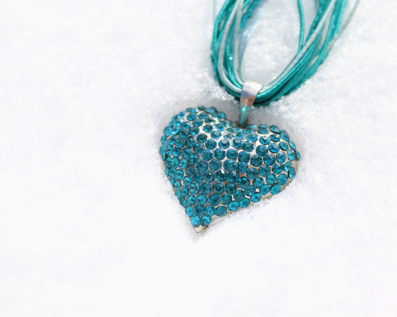 Голубой кулон в форме сердца на снегу