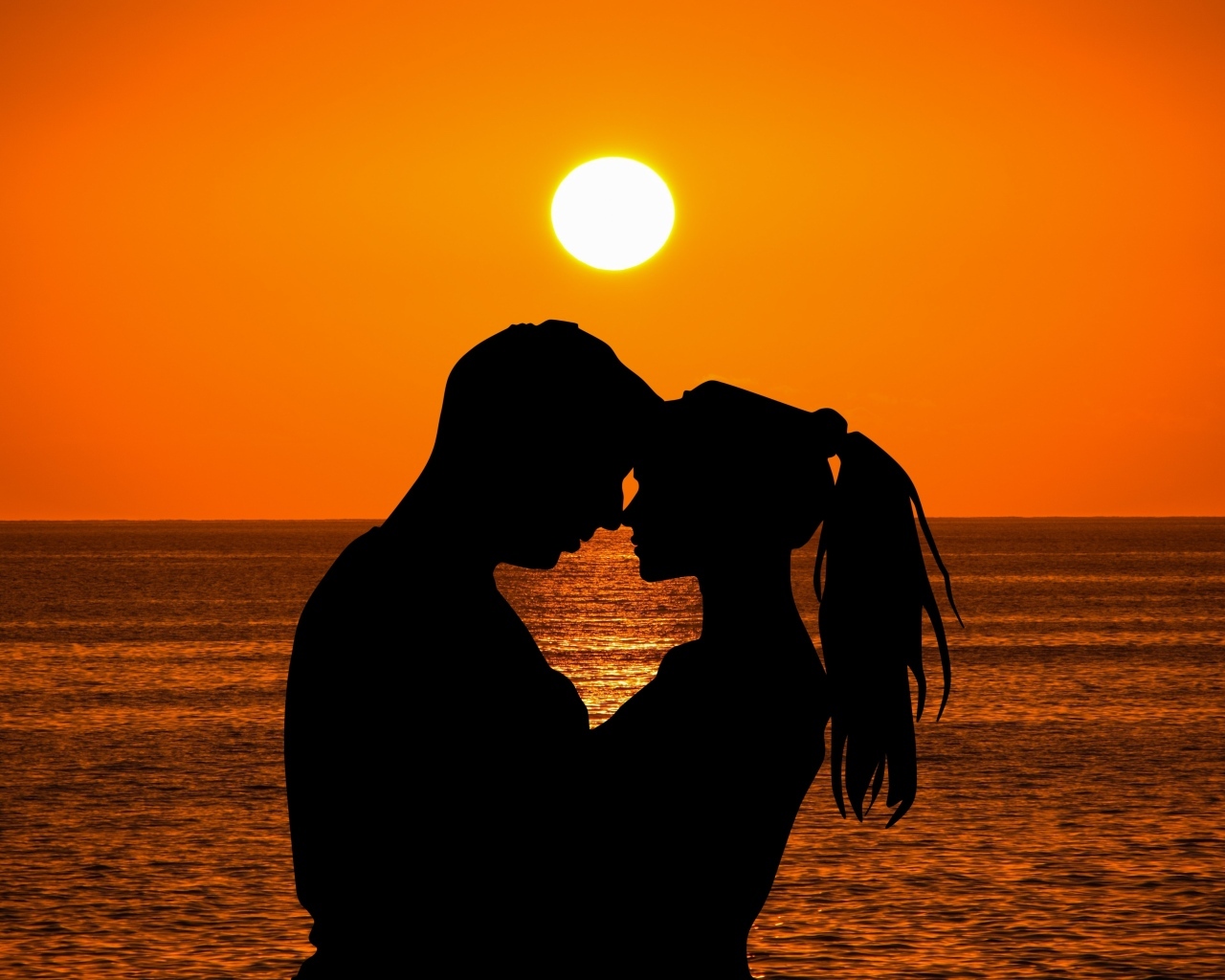 Влюбленная пара на закате солнца у моря