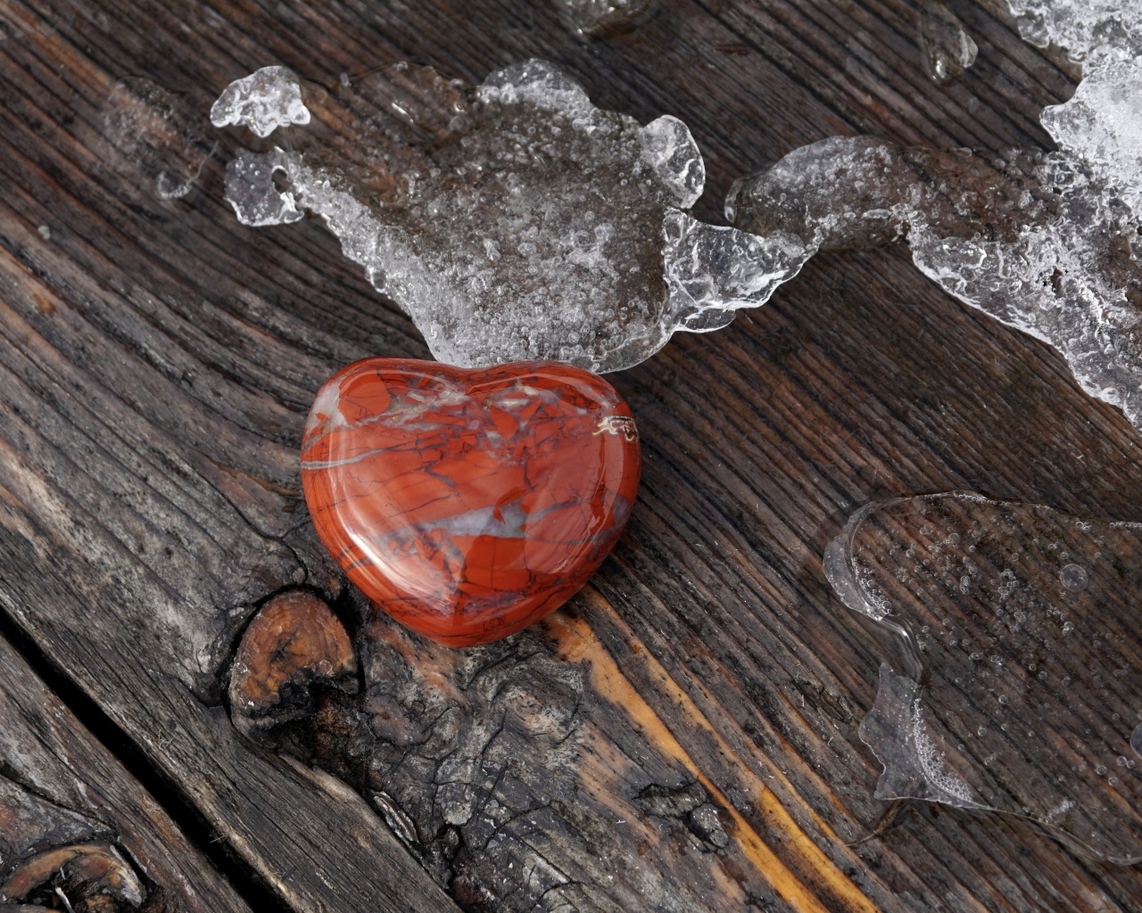 Сердце из камня на деревянной лавке с тающим снегом