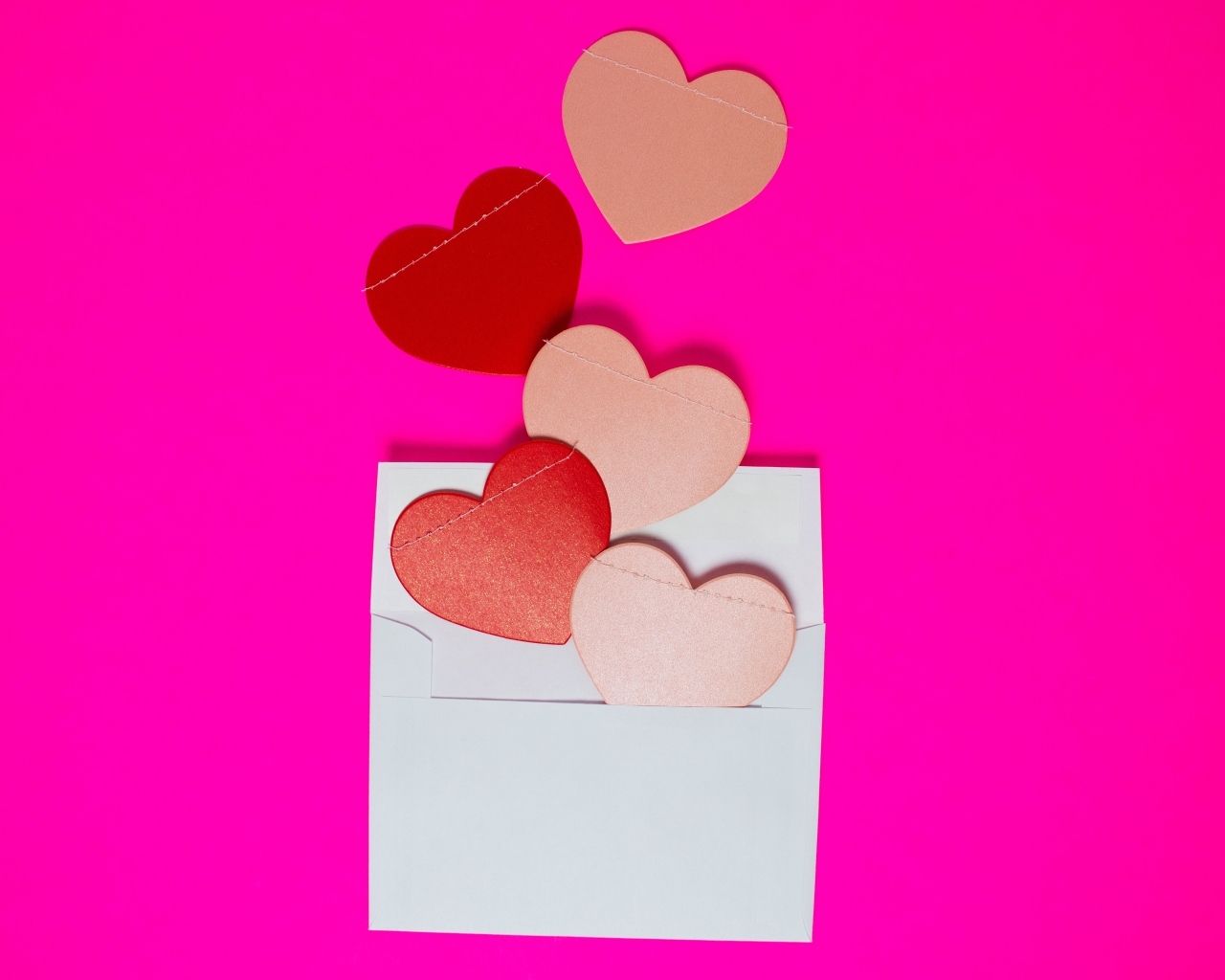 Сердечки с белым конвертом на розовом фоне