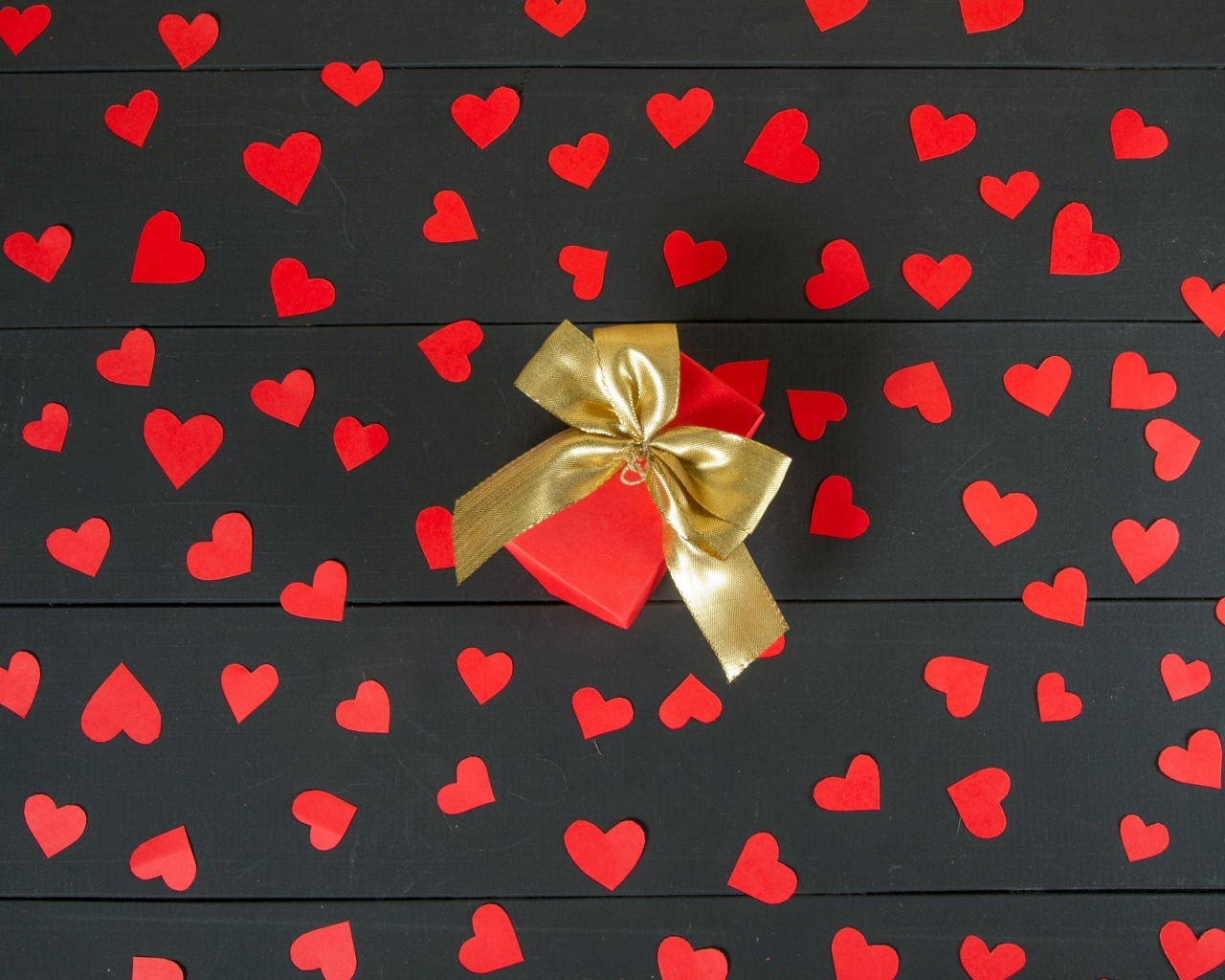 Много маленьких бумажных сердечек с подарком на столе