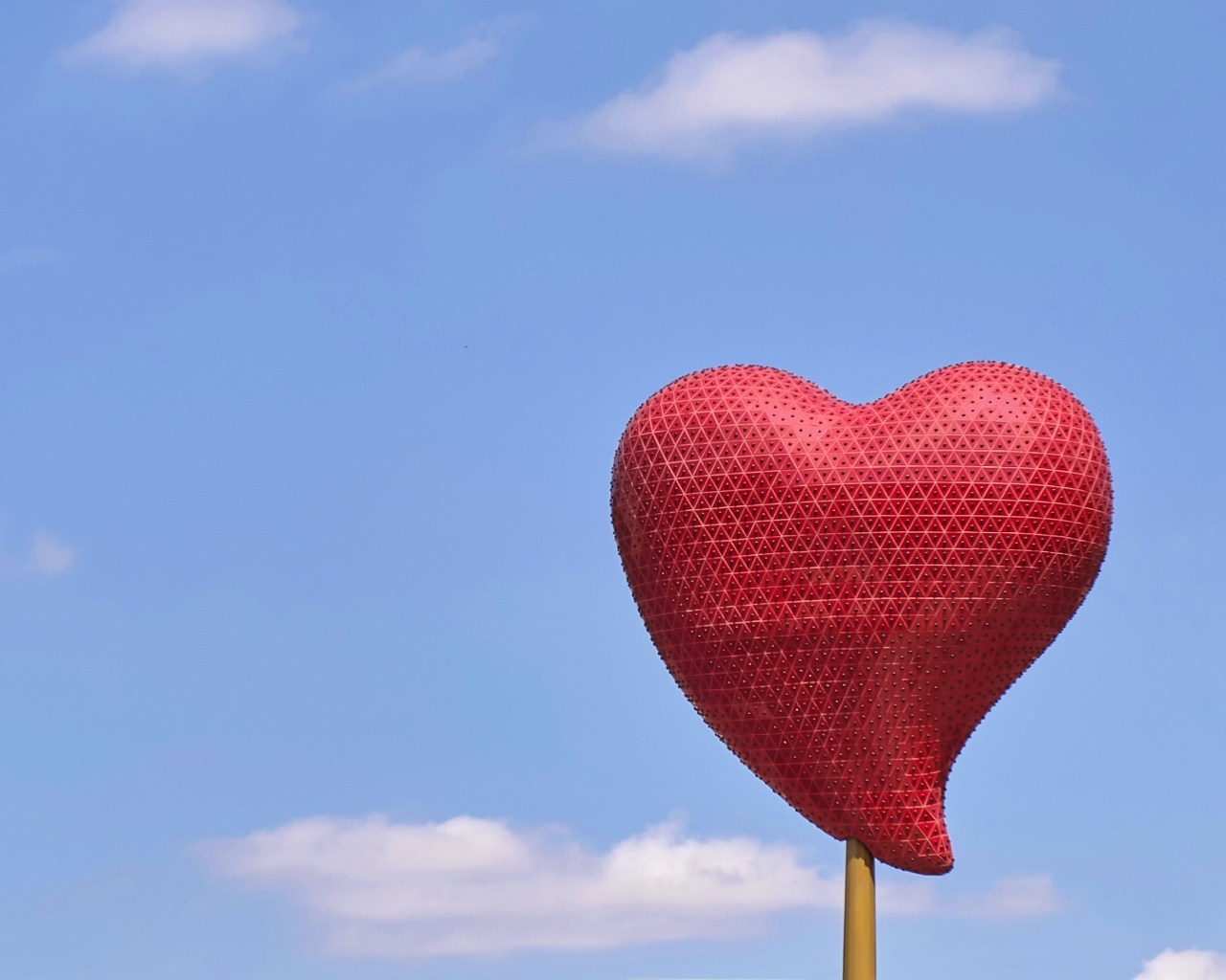 Красное сердце на палочке на фоне неба