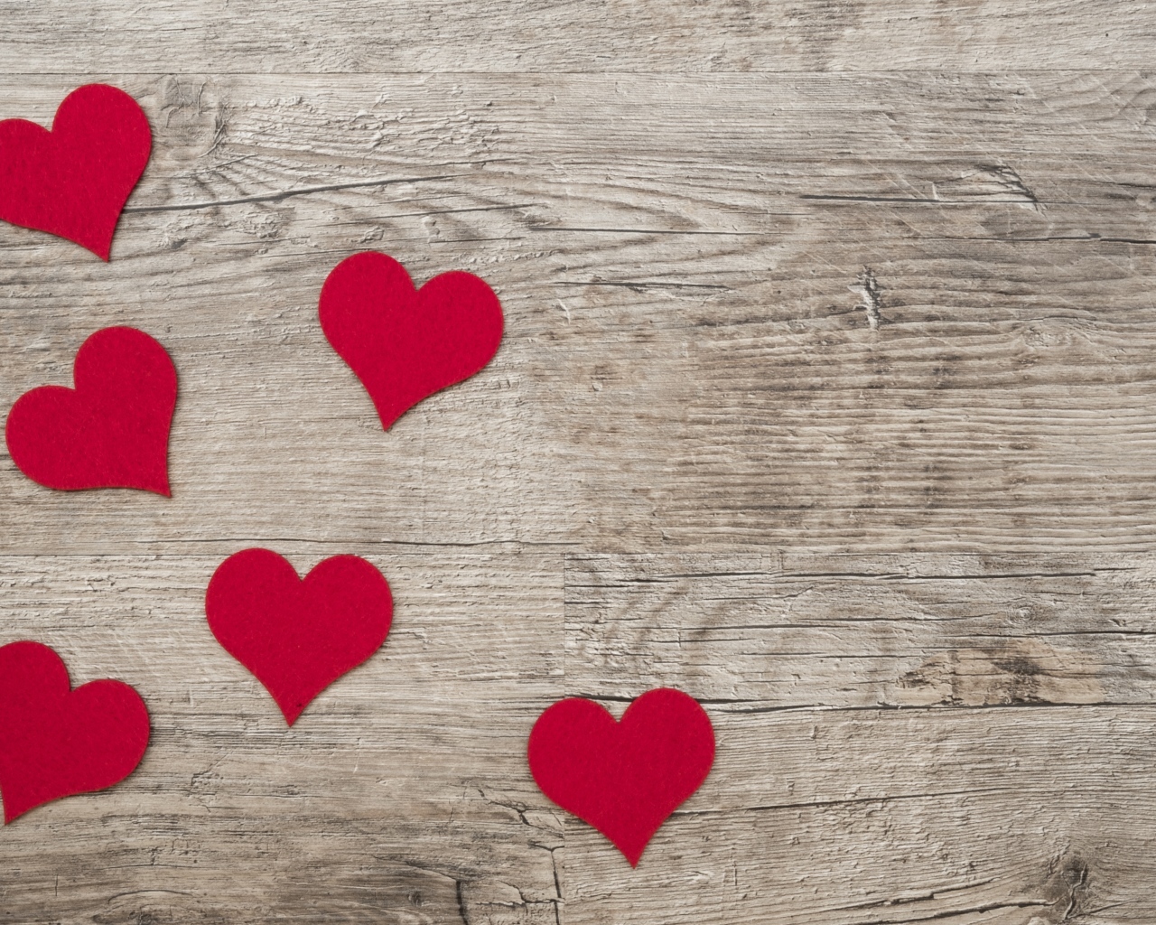 Маленькие красные сердечки на деревянном фоне