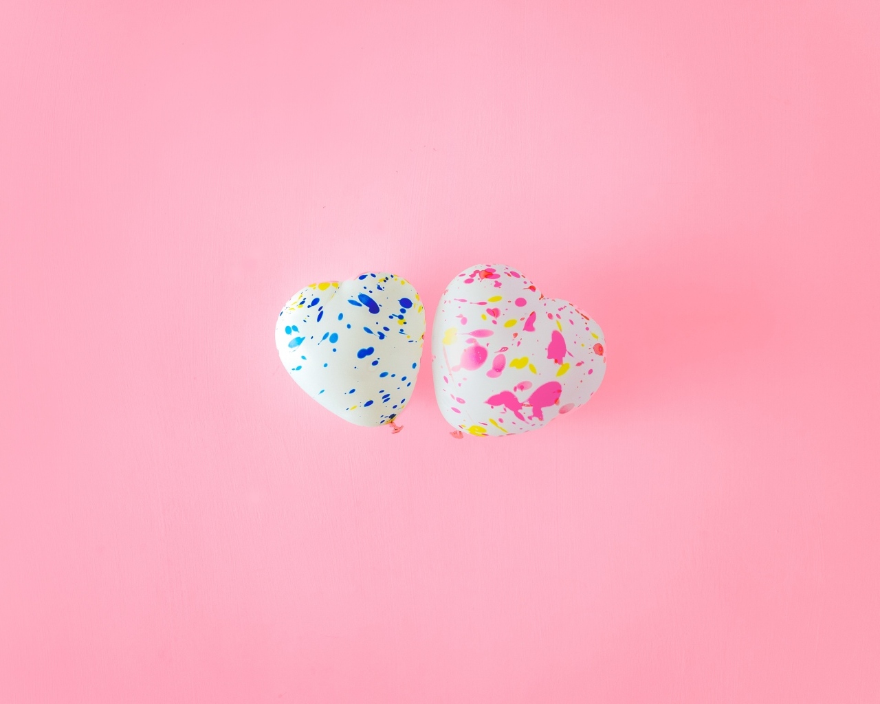 Два шарика в форме сердца на розовом фоне