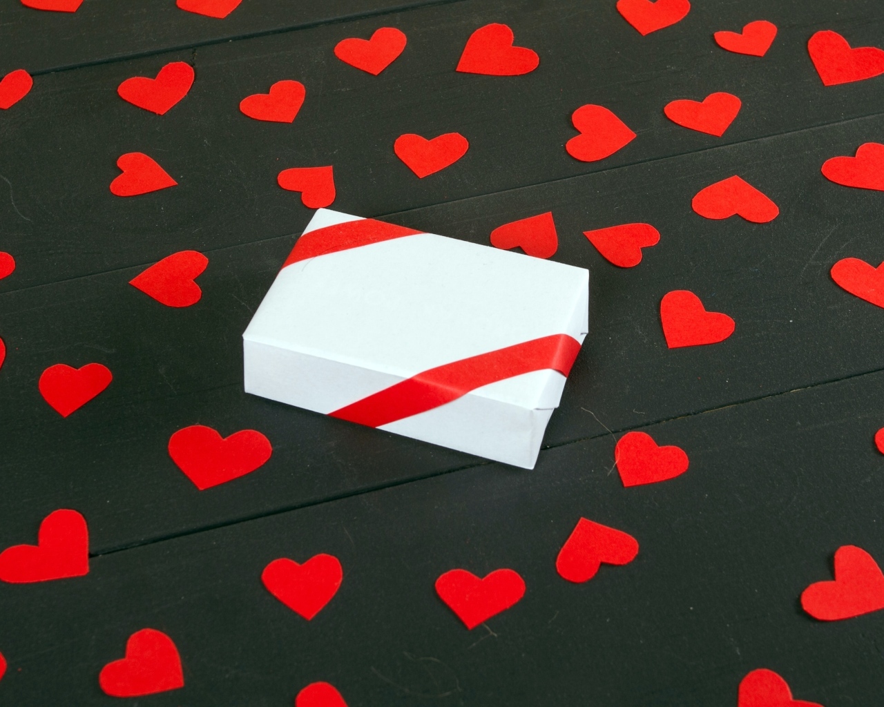Белая коробка с маленькими бумажными сердечками на столе