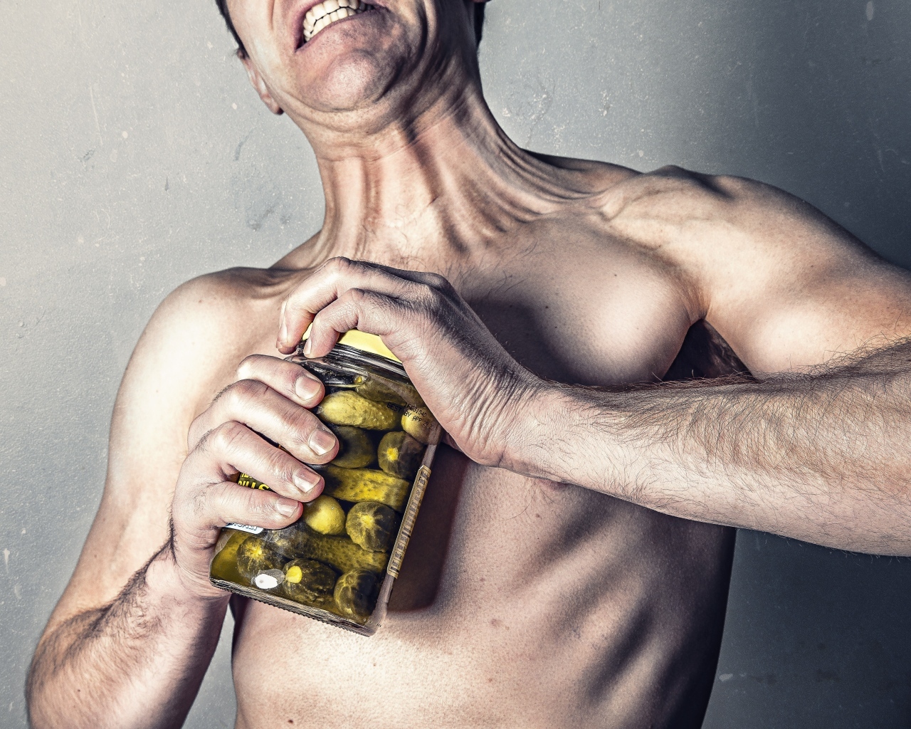 Мужчина открывает банку огурцов