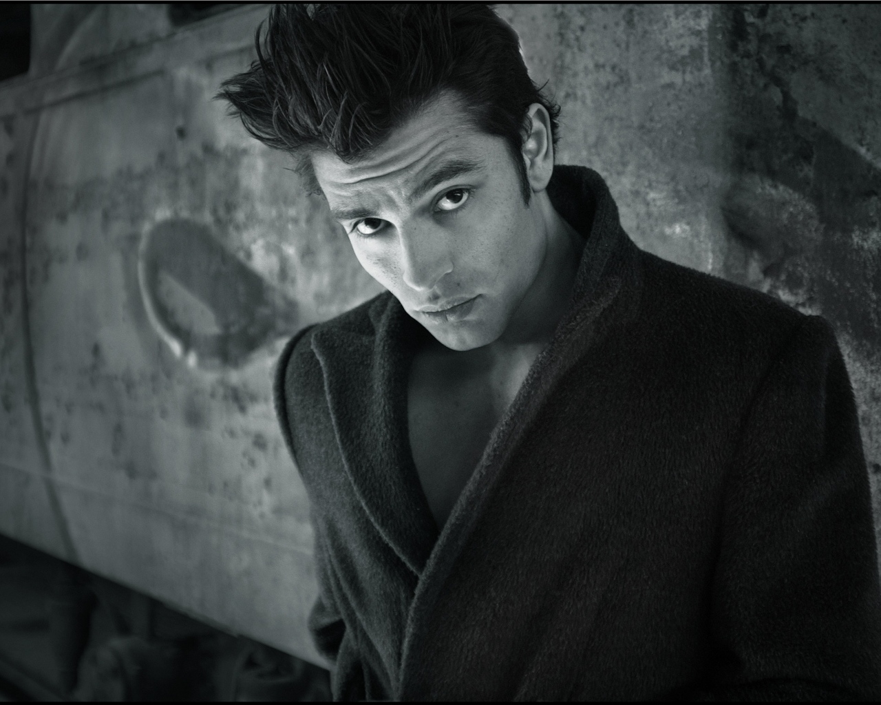 Красивый мужчина в черном пальто у стены