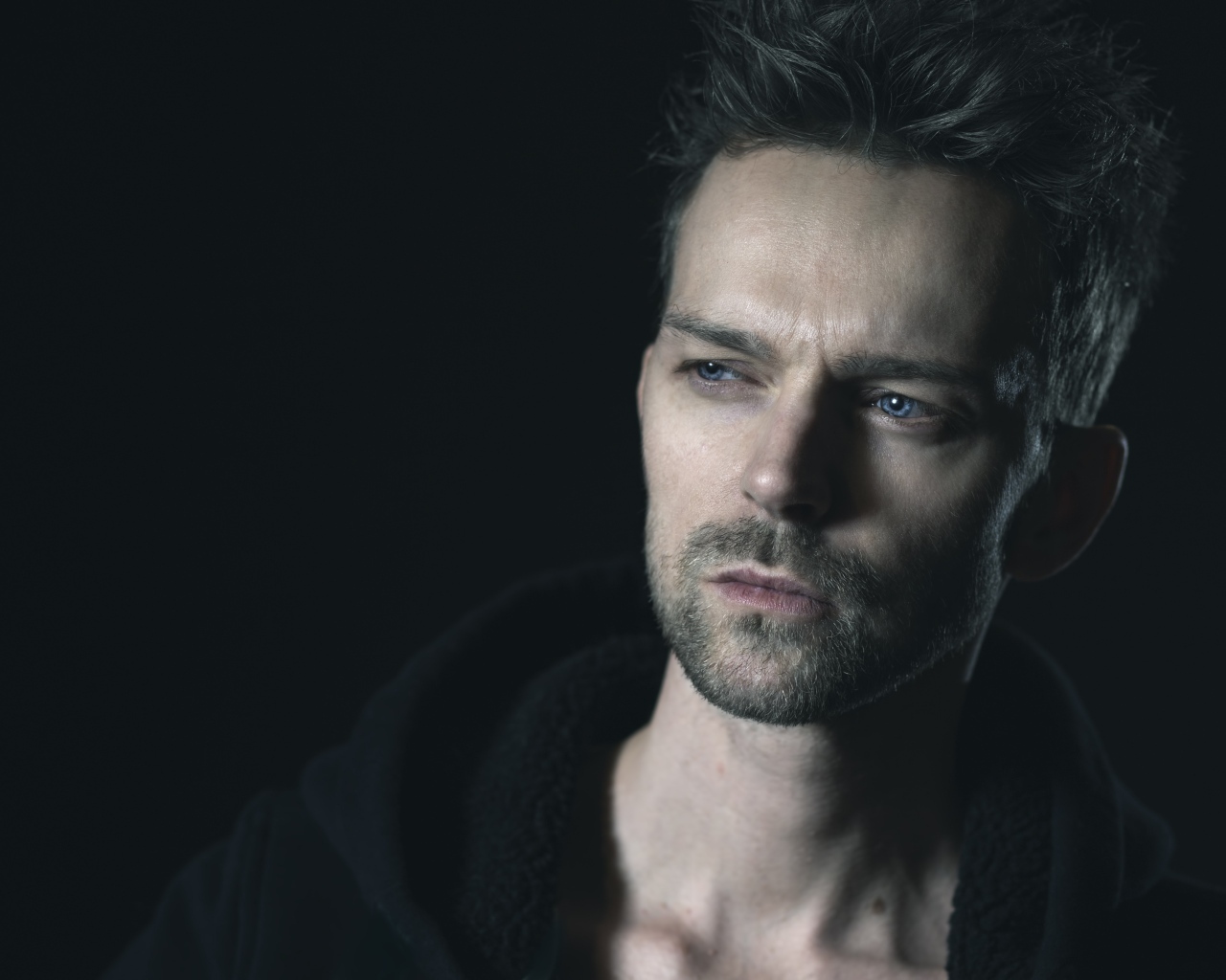 Серьезный голубоглазый мужчина на черном фоне