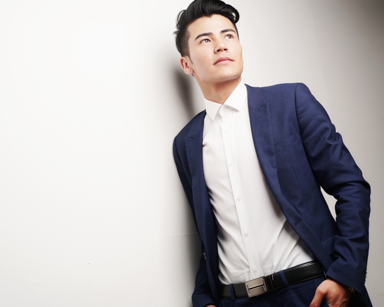 Молодой мужчина в костюме у стены