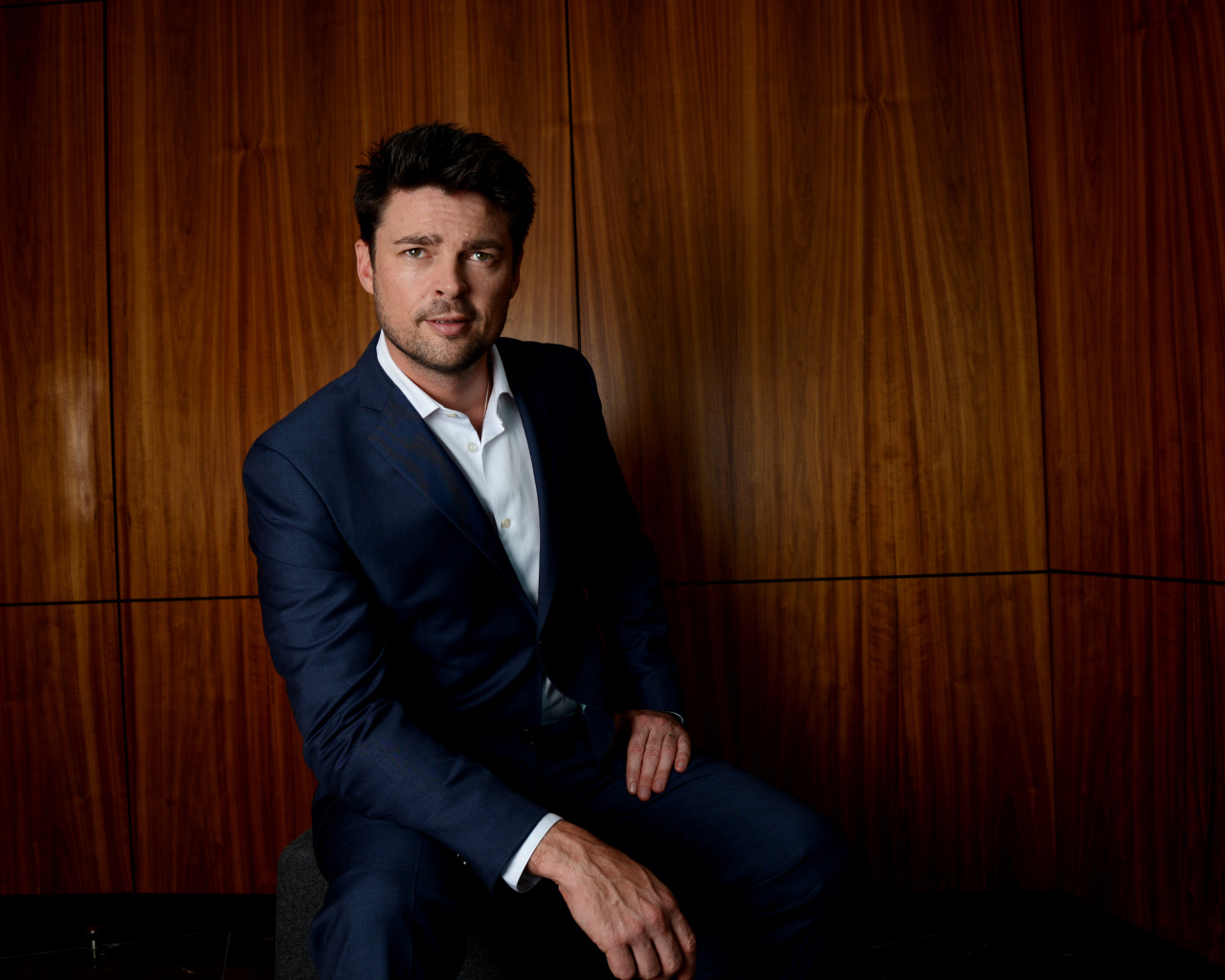 Актер Карл Урбан в костюме на фоне стены