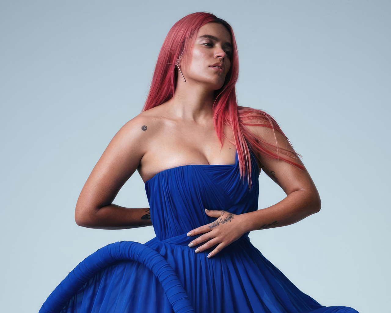 Певица Karol G в синем платье на сером фоне